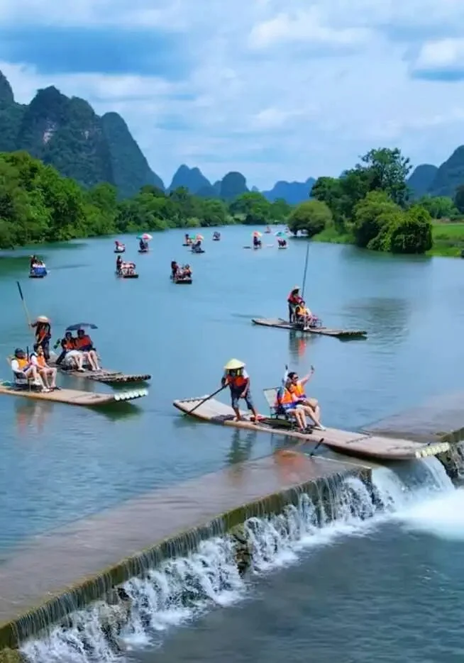 A bamboo raft dropping over a small dam on the Yulong River in Yangshuo