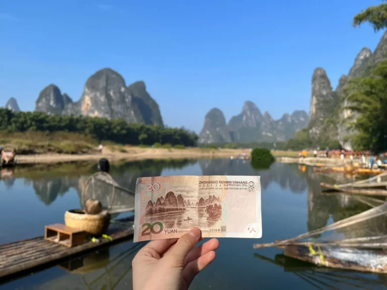 Holding a 20 RMB note against Xingping karst backdrop